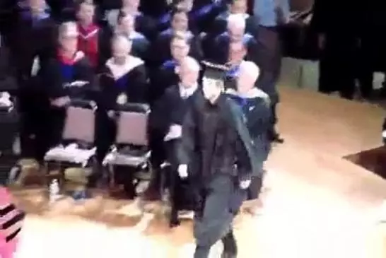 Lors d’une remise de diplome , un jeune homme trébuche devant les marches .