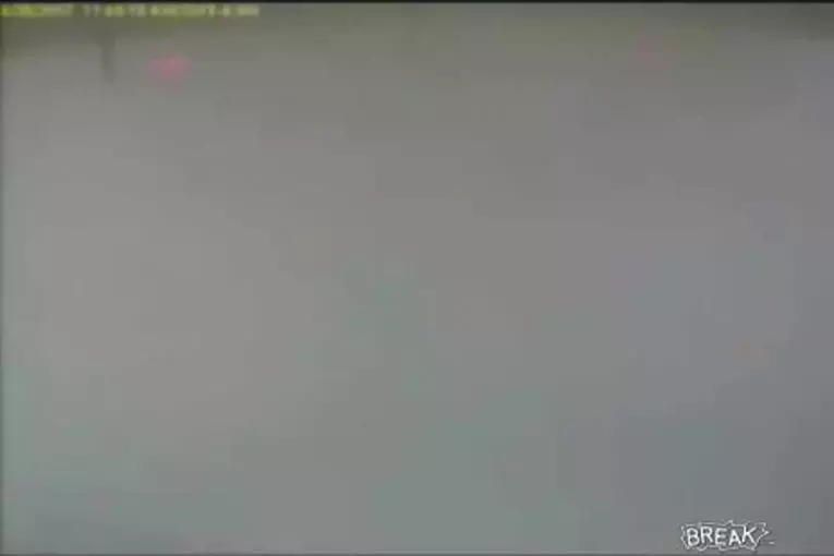 Une femme blonde appuie sur le bouton d'urgence d'une station essence