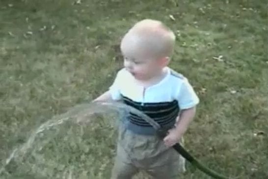 Enfant qui boit au tuyau d’arrosage