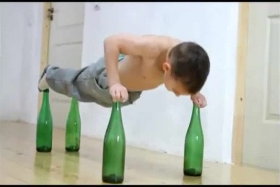 Cet enfant fait des pompes sur des bouteilles en verre