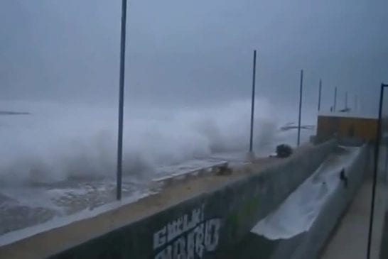 Vague géante surprend un homme sur un mur