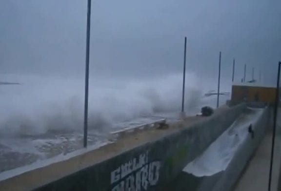 Vague géante surprend un homme sur un mur